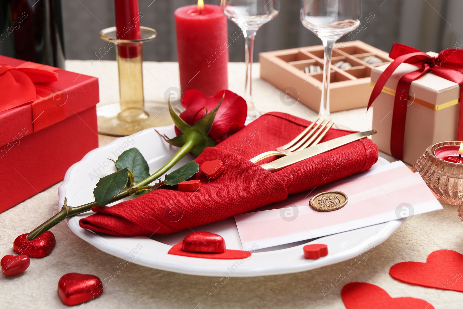 Photo of Romantic place setting with red rose on table, closeup. Valentine's day celebration