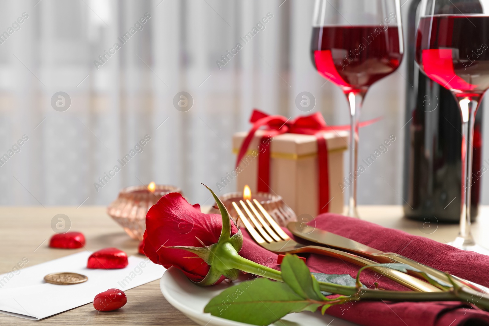 Photo of Romantic place setting with red rose on table, closeup. Valentine's day celebration