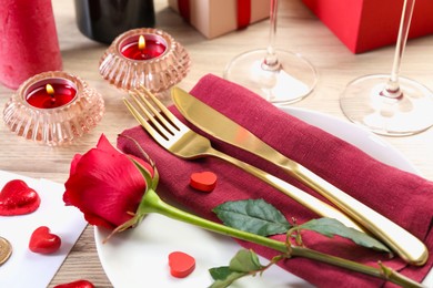 Photo of Romantic place setting with red rose on white table, closeup. Valentine's day celebration