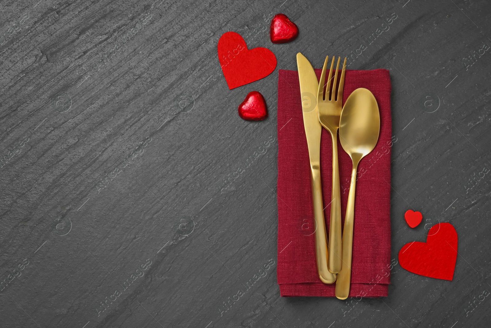 Photo of Romantic place setting with red hearts and cutlery on black table, top view. Valentine's day celebration