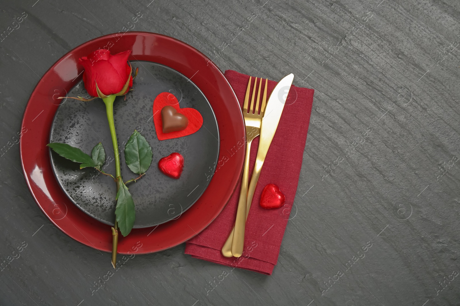 Photo of Romantic place setting with rose and plates on black table, top view. Valentine's day celebration