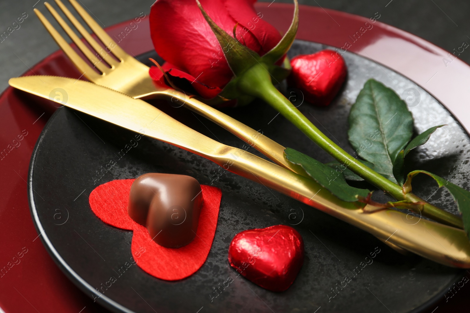 Photo of Romantic place setting with rose and plates on table, closeup. Valentine's day celebration