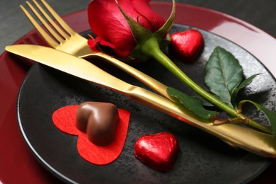 Photo of Romantic place setting with rose and plates on table, closeup. Valentine's day celebration