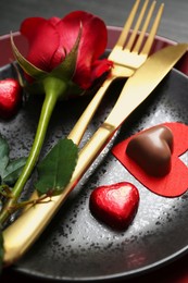 Romantic place setting with rose and plates on table, closeup. Valentine's day celebration