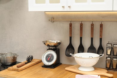 Photo of Retro mechanical kitchen scale and other utensils on wooden countertop indoors