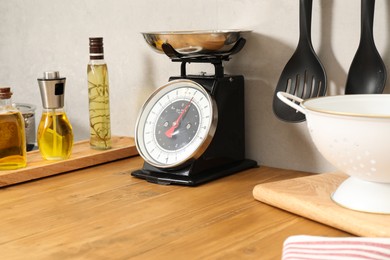 Photo of Retro mechanical kitchen scale, oils and utensils on wooden countertop indoors