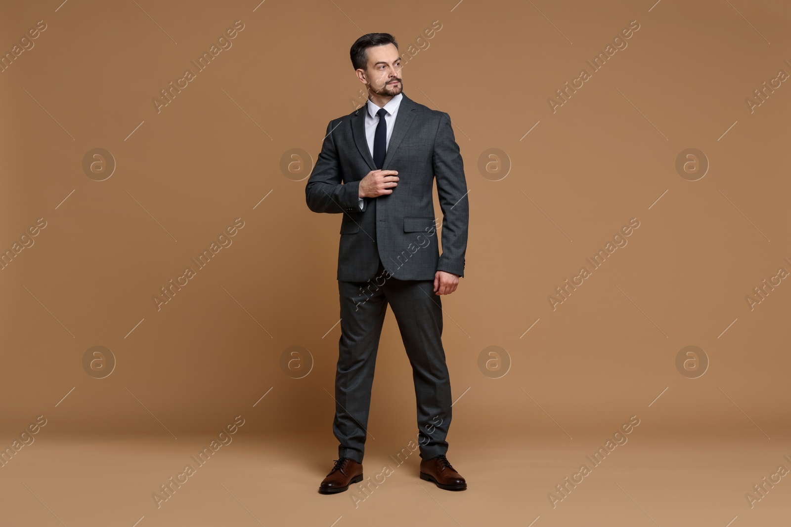 Photo of Confident man in classic suit on brown background