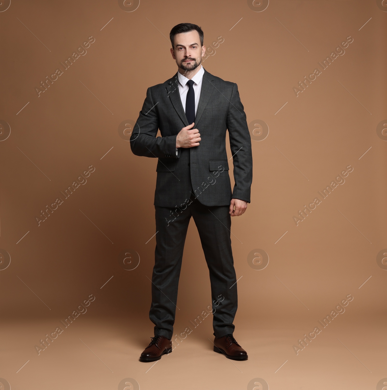 Photo of Confident man in classic suit on brown background