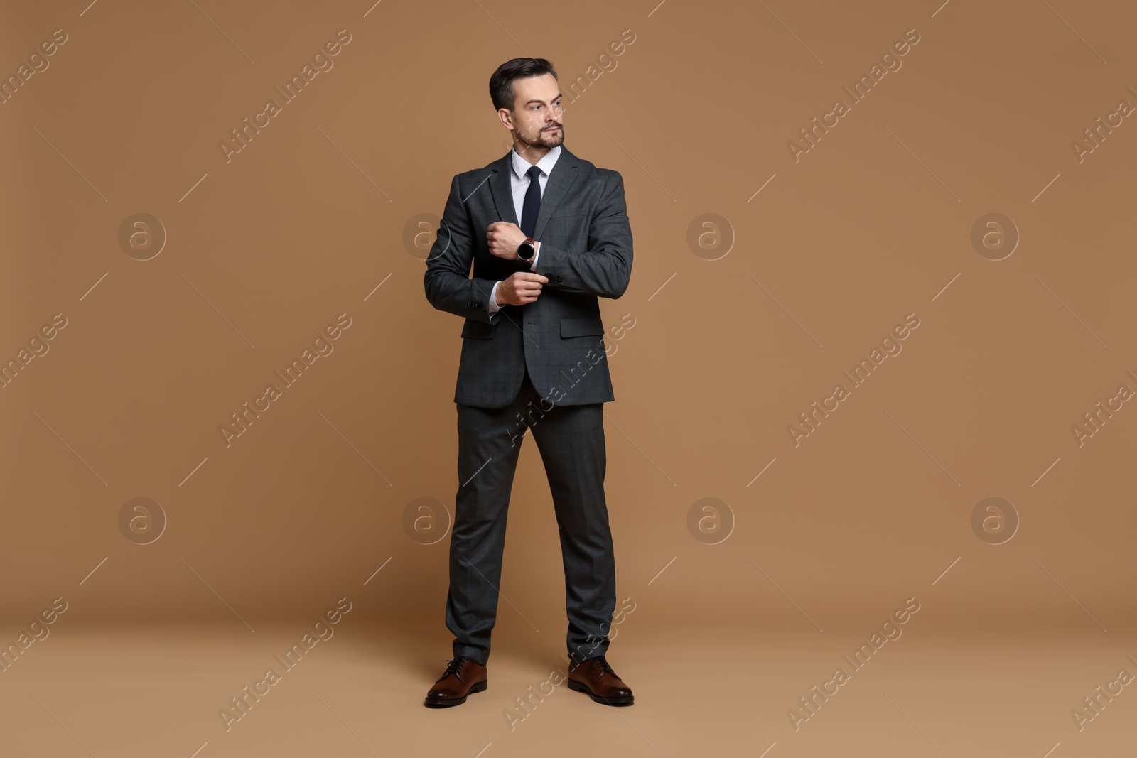 Photo of Confident man in classic suit on brown background