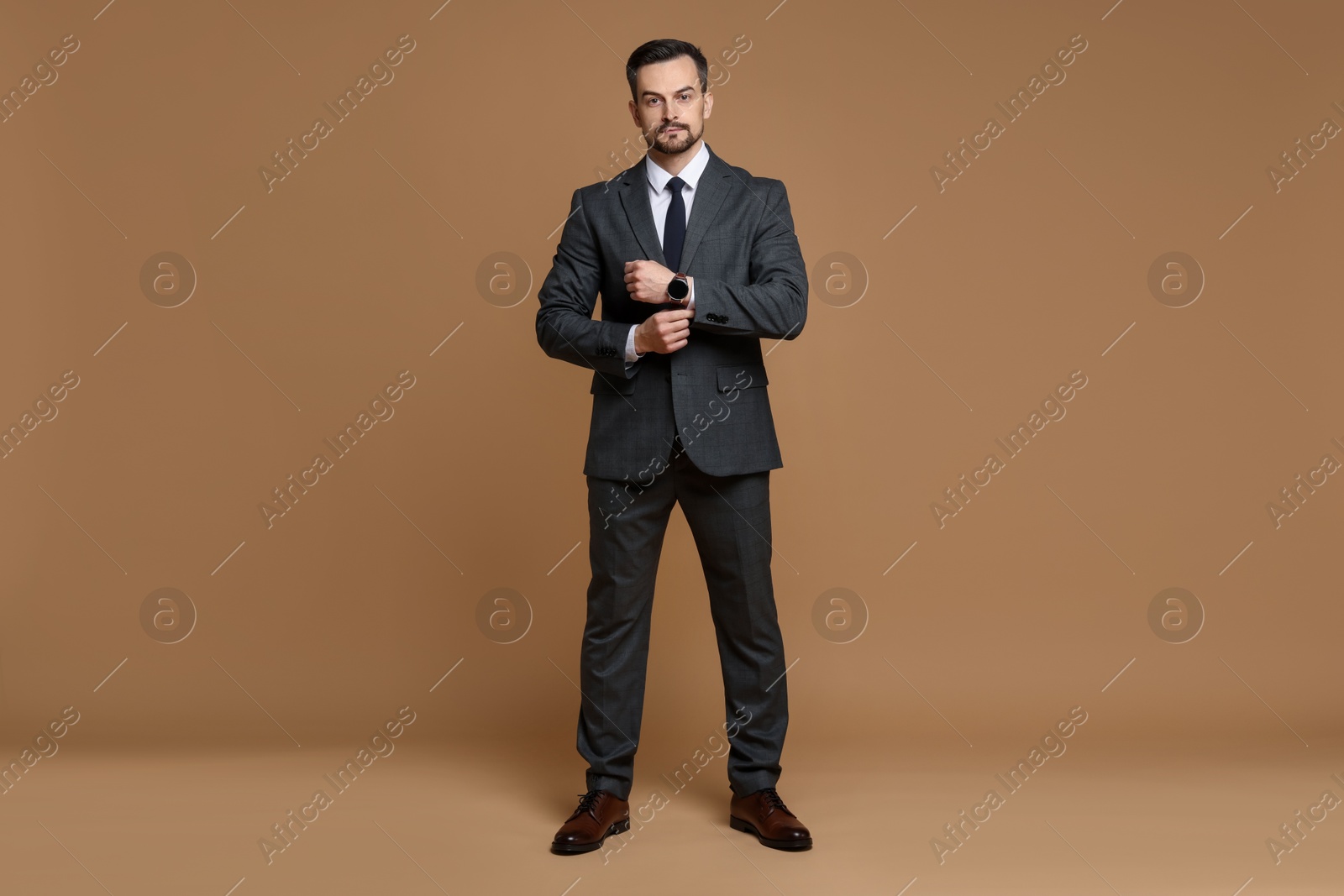 Photo of Confident man in classic suit on brown background