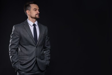 Confident man in classic suit on black background. Space for text