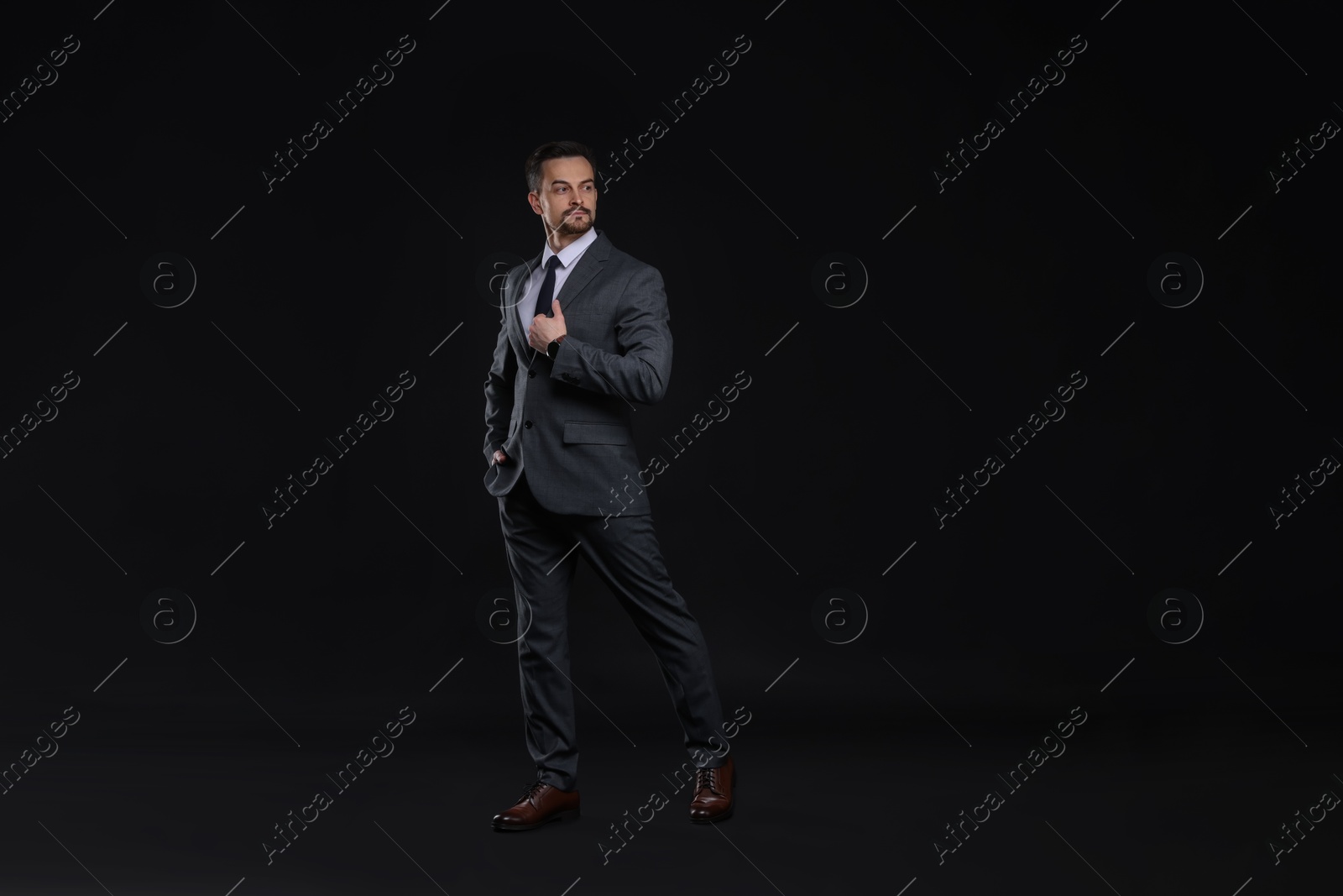 Photo of Confident man in classic suit on black background