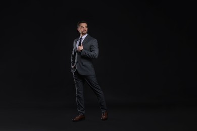 Confident man in classic suit on black background