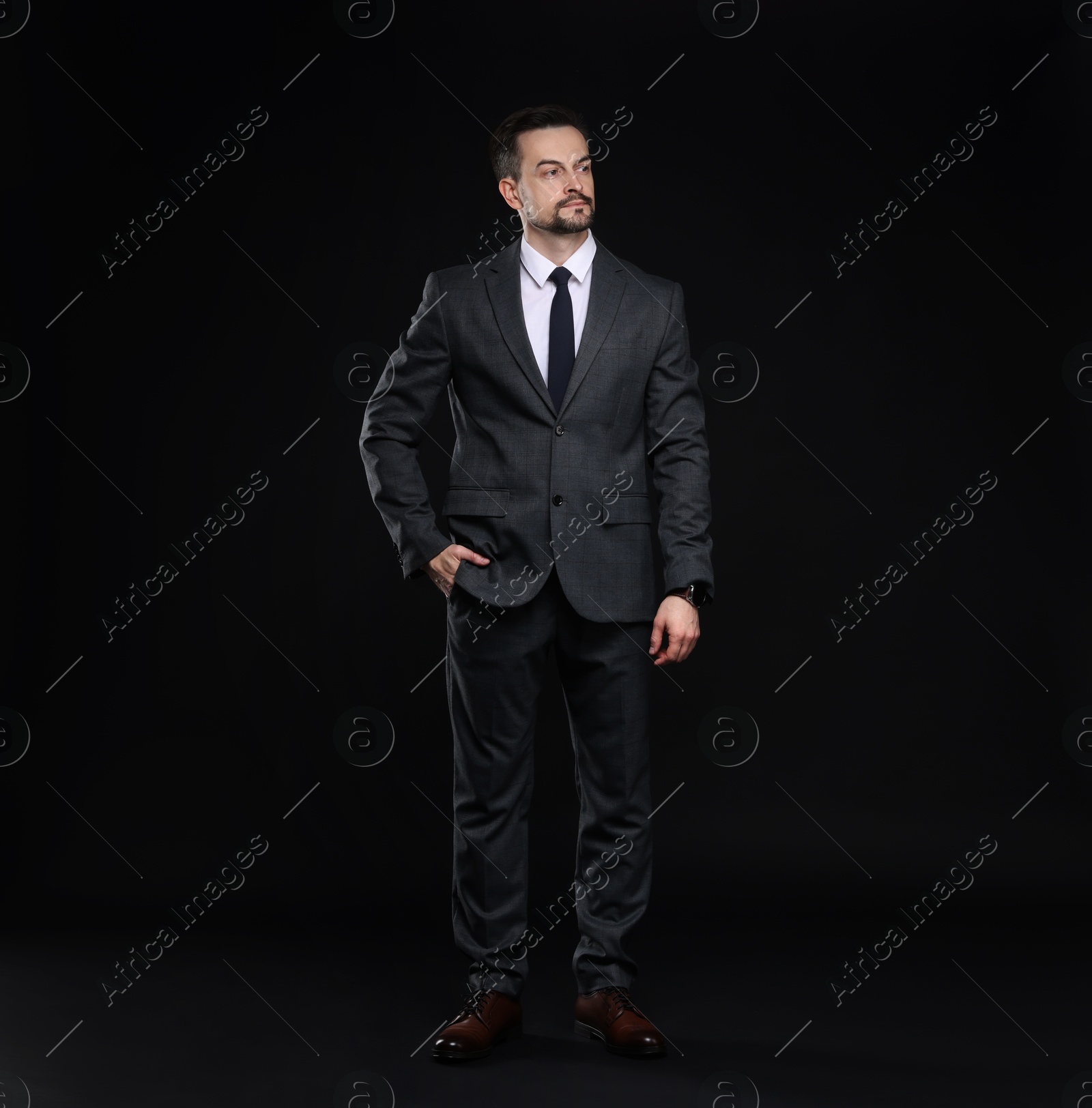 Photo of Confident man in classic suit on black background