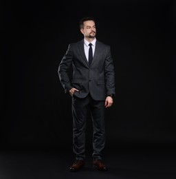 Confident man in classic suit on black background