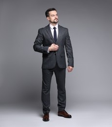 Confident man in classic suit on grey background