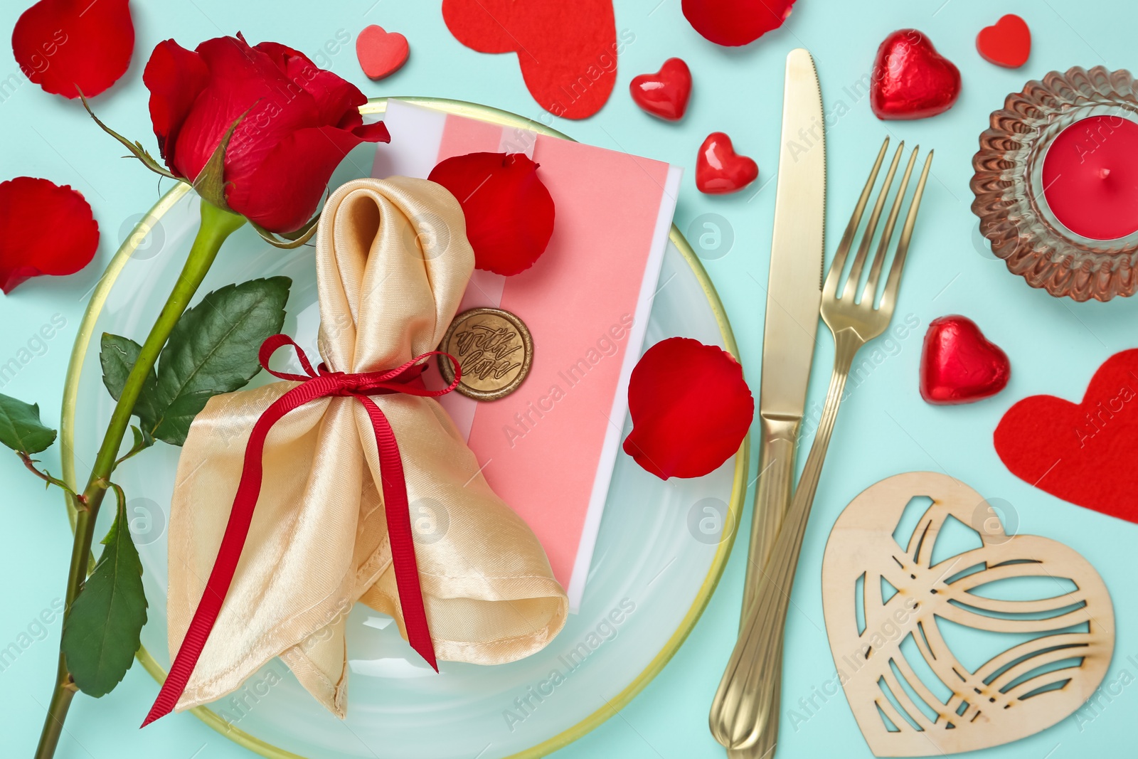 Photo of Romantic place setting with cutlery, hearts and red rose on light blue background, flat lay. Valentine's day celebration