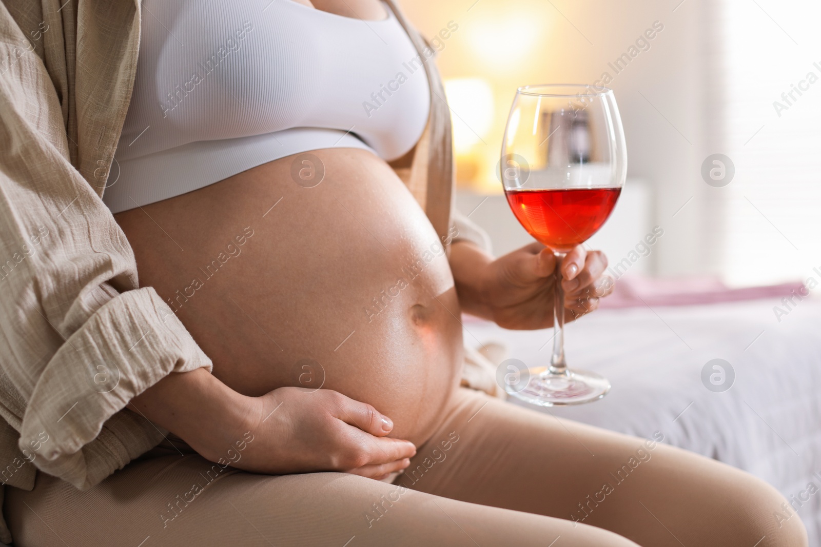 Photo of Pregnant woman with glass of red wine at home, closeup