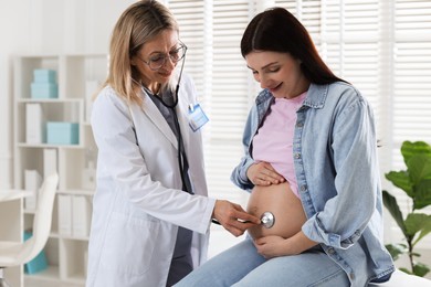 Pregnancy checkup. Doctor with stethoscope listening baby's heartbeat in patient's tummy indoors