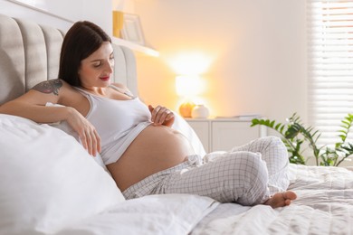 Photo of Beautiful pregnant woman with cute belly on bed at home