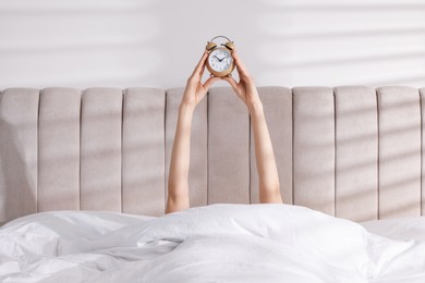 Photo of Woman with alarm clock in bed at home, closeup. Good morning