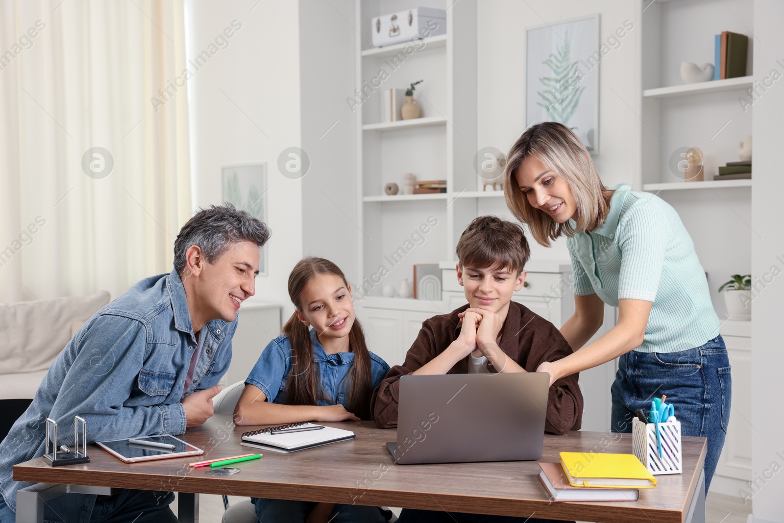 Photo of Happy parents and their children doing homework at table indoors