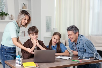 Photo of Happy parents and their children doing homework at table indoors