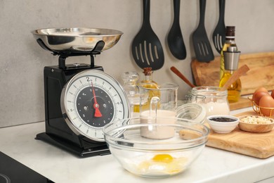 Photo of Retro mechanical kitchen scale and different food products on white marble countertop indoors