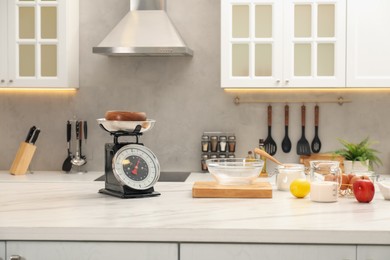 Photo of Retro mechanical kitchen scale and different food products on white marble table indoors