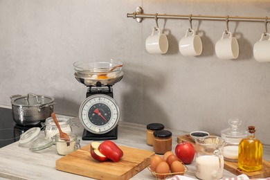 Photo of Retro mechanical kitchen scale and different food products on wooden countertop indoors