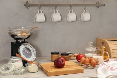 Photo of Retro mechanical kitchen scale and different food products on wooden countertop indoors