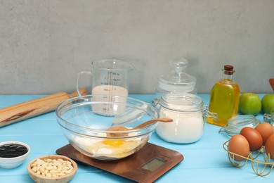 Electronic kitchen scale and different food products on light blue wooden table indoors