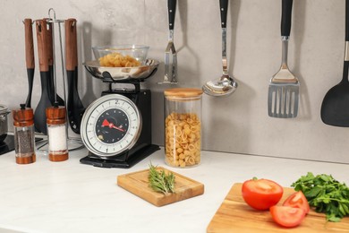 Photo of Retro mechanical kitchen scale, other utensils and different food products on white marble countertop indoors