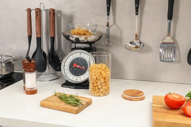 Photo of Retro mechanical kitchen scale, other utensils and different food products on white marble countertop indoors