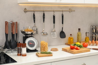 Photo of Retro mechanical kitchen scale, other utensils and different food products on white marble countertop indoors