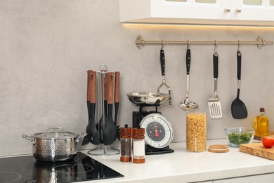 Photo of Retro mechanical kitchen scale, other utensils and different food products on white marble countertop indoors