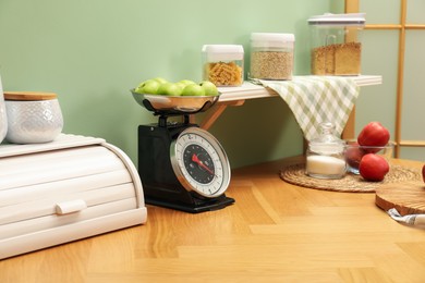 Photo of Kitchen scale, products and cooking utensils on wooden table