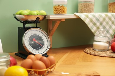 Kitchen scale, products and cooking utensils on wooden table