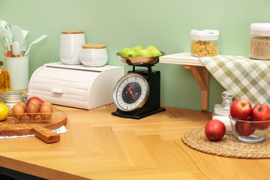 Kitchen scale, products and cooking utensils on wooden table