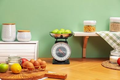 Kitchen scale, products and cooking utensils on wooden table