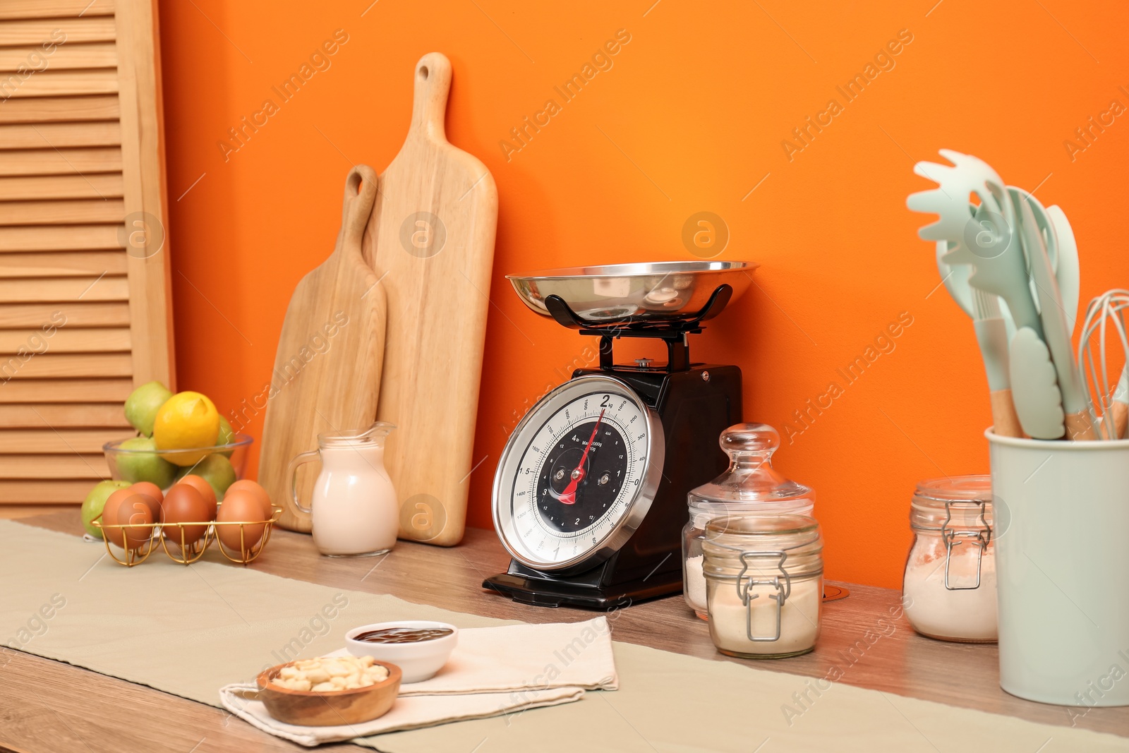 Photo of Kitchen scale, products and cooking utensils on wooden table