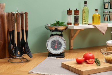 Kitchen scale, products and cooking utensils on wooden table