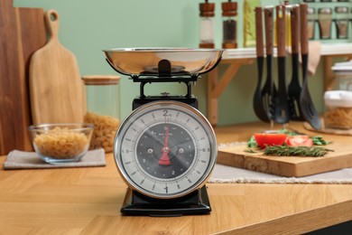 Kitchen scale, products and cooking utensils on wooden table