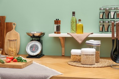 Kitchen scale, products and cooking utensils on wooden table