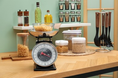 Photo of Kitchen scale, products and cooking utensils on wooden table