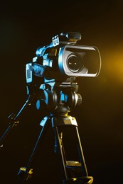 Photo of Modern video camera with tripod on black background