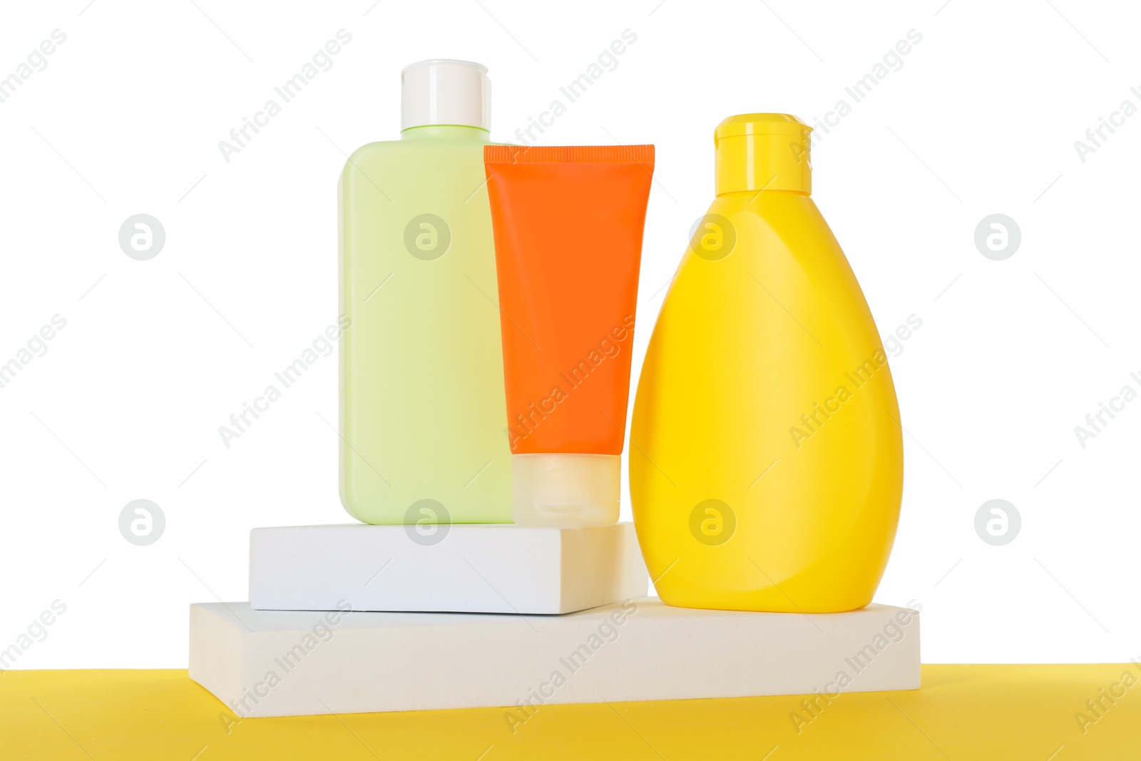 Photo of Different sun protection products and podiums on yellow surface against white background