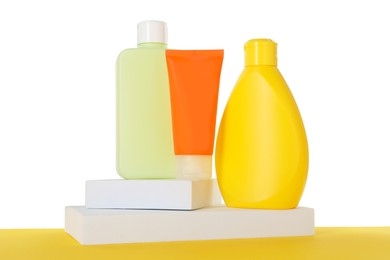 Photo of Different sun protection products and podiums on yellow surface against white background