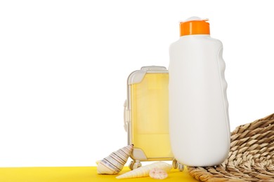 Photo of Bottle of sun protection product and seashells on yellow surface against white background