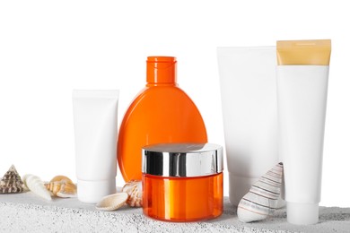 Photo of Different sun protection products and seashells on concrete surface against white background